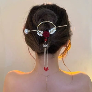 Close-up of a vintage golden hair pin with a red rose and elegant silver tassels