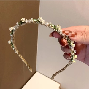 Elegant gold woven headband featuring white lily of the valley flowers and pearls