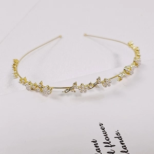 Close-up of golden metal leaf headband with white pearls and sparkling rhinestones