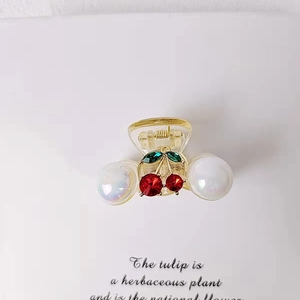 Detail of transparent cherry hair claw clip with red rhinestones and iridescent pearls