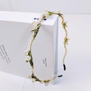 Detail view of handmade lily of the valley headband with white pearls and gold wire