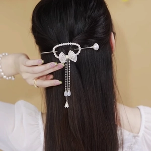 Detail of vintage pearl hair stick with butterfly bow and long hanging tassels