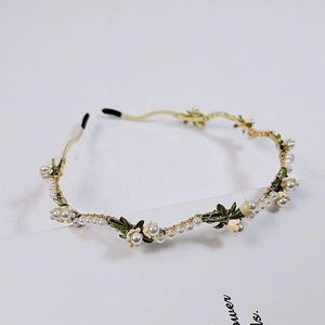 Detailed close-up of handmade lily of the valley headband with white pearls and gold wire