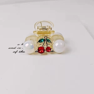 Detail of transparent cherry hair claw with red rhinestones and iridescent pearls