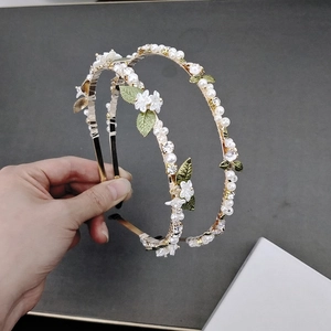 Detailed view of floral pearl headbands with golden metal leaves and white flowers