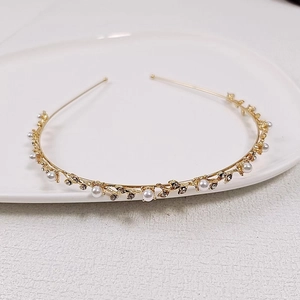 Detailed shot of golden vine headband with white pearls and rhinestones on ceramic tray