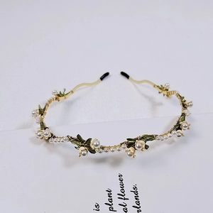 Close-up of handmade lily of the valley headband with white pearls and green leaves
