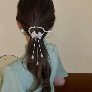 Detailed view of pearl bow hair pin with long tassel for elegant buns and hairstyles