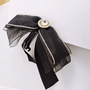 Elegante molletta per capelli con fiocco in rete nera, strass e perle su sfondo bianco