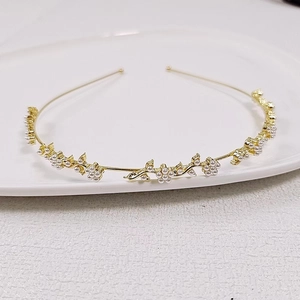 Close-up of golden leaf headband with white pearls on a ceramic jewelry tray