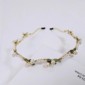 Detailed view of handmade lily of the valley headband with white pearls and green leaves