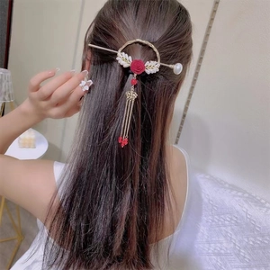 Detailed close-up of a vintage hair pin with a red rose and pearl tassels in hair