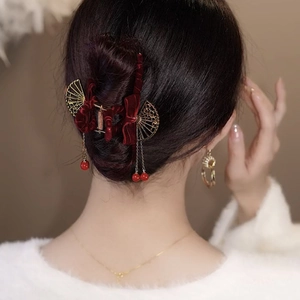 Dettaglio della pinza per capelli in velluto rosso con ventagli dorati e nappe di perle