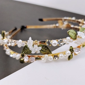 Detail of elegant floral headband with white flowers, green leaves, pearls and crystals