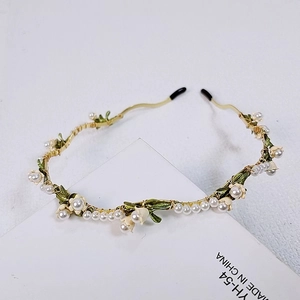 Detailed macro shot of handmade lily of the valley headband with white pearls and gold wire