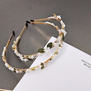 Close-up of elegant floral headbands with silk petals, green leaves and pearls