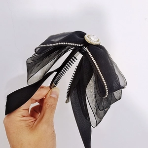 Dettaglio della clip per capelli a banana nera con fiocco in rete e strass