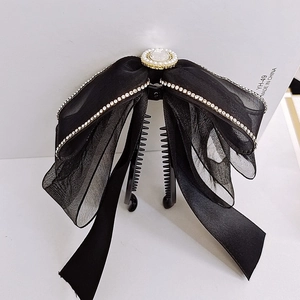 Dettaglio della clip per capelli con fiocco in tulle nero, strass e grande perla centrale