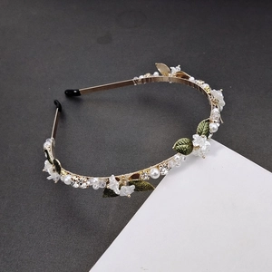 Elegant floral pearl headband with rhinestones and green leaves on a gold metal frame