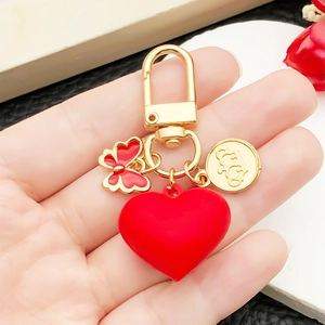Red 3D heart keychain with gold crown coin and butterfly charm on hand held display