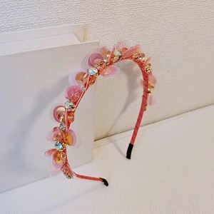 Cerchietto con paillettes rosa e arancioni e strass di cristallo su sfondo bianco