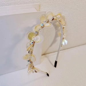 Dettaglio del cerchietto sottile dorato con petali di paillettes e cristalli sfaccettati