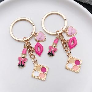 Gold makeup keychain set with pink enamel lipstick heart and eye shadow tray charms
