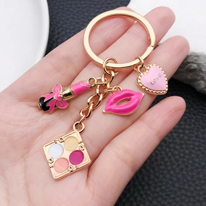 Chic enamel makeup keychain with lipstick and lip charms held against a dark background
