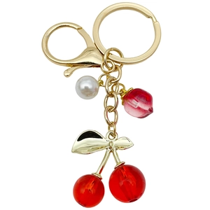 Creative translucent red cherry keychain with white pearl and gold leaf on white background