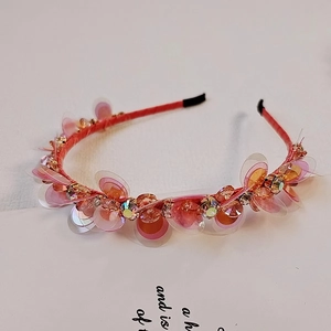Dettaglio del cerchietto rosa arancio con paillettes e strass scintillanti