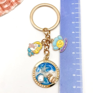 Macro detail of ocean-themed keychain featuring mermaid and shell charms with ruler scale