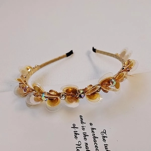 Dettaglio del cerchietto dorato con fiori di cristallo e paillettes dal design dolce