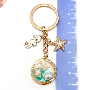 Détail du porte-clés nautique avec breloques hippocampe et étoile de mer près d'une règle