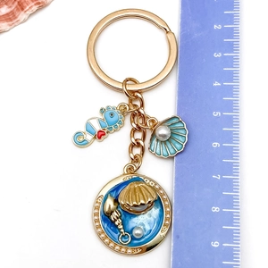 Détail du porte-clés marin montrant l'hippocampe bleu et le pendentif coquillage perlé