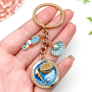 Porte-clés thème marin avec hippocampe bleu pétoncle et perle sur un anneau doré