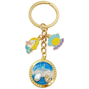 Golden keychain with ocean-themed charms featuring a mermaid, starfish, and shell pearls