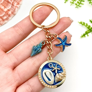 Porte-clés nautique doré avec étoile de mer bleue, coquillage et perles pour sacs