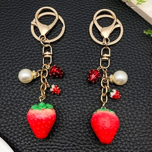 Creative red resin strawberry keychain with pearls and diamond-studded gold metal accents