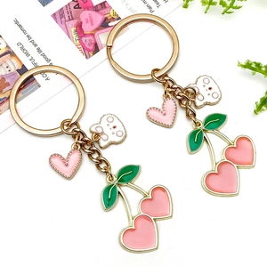 Detail of pink heart cherry and white bear charms on a golden alloy keychain pendant