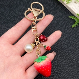 Creative strawberry keychain with red berries and pearl hanging from a golden metal ring