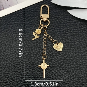 Porte-clés croix coeur rose doré avec dimensions affichées sur une surface en cuir