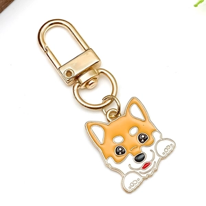 Detailed macro view of a cute cartoon Shiba Inu keychain with golden lobster clasp and enamel finish