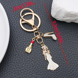 Modischer goldener Schlüsselanhänger mit weißen High Heels, Lippenstift und Kleideranhänger