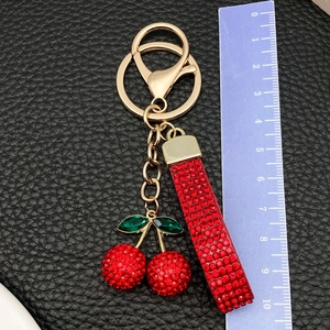 Detailed view of red rhinestone cherry keychain with green leaves and gold clasp