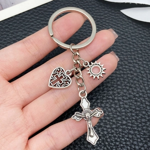 Portachiavi vintage in argento con crocifisso, cuore e sole su sfondo in pelle