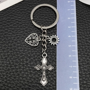 Dettaglio dei ciondoli croce, cuore e sole in argento su portachiavi con righello di misura