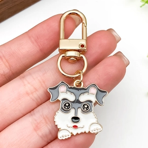 Cute schnauzer enamel keychain in grey and white with gold lobster clasp held in hand