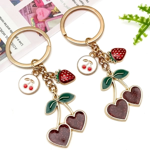 Detailed macro view of gold-plated cherry and heart strawberry pendants on keychains