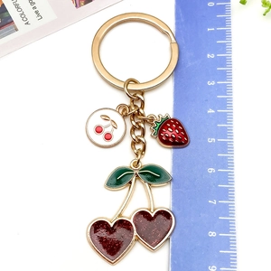 Detail shot of cherry and strawberry fruit charms showing scale with a blue ruler