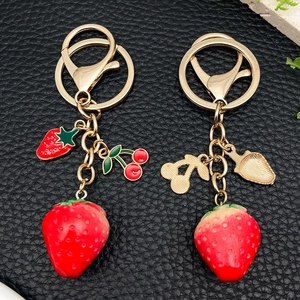 Resin strawberry and cherry keychain with gold lobster clasp on premium black texture